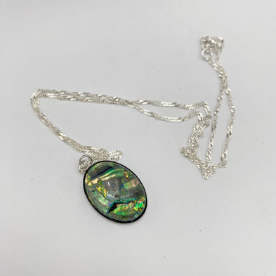 Silver necklace with a green and black pendant on a white background